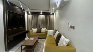 Una sala de estar moderna con un televisor de pantalla plana, dos sofás, una mesa de centro y un equipo de aire acondicionado.