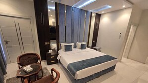 A modern bedroom with a large bed, a desk, and a chair. - Al Jawhara Suites Serviced Apartments (Taif)