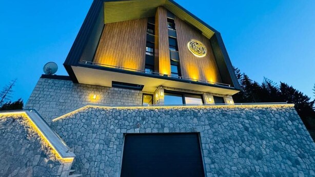 Un edificio moderno con fachada de piedra, una puerta de garaje grande y una antena parabólica.