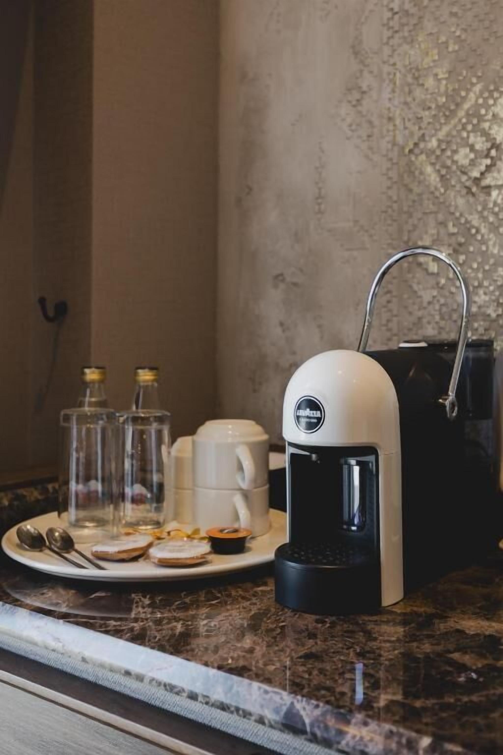 A kitchen counter with a coffee maker, a plate with food items, and two glass bottles.