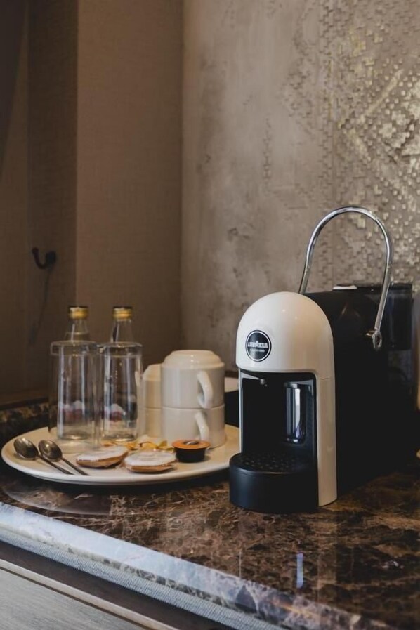 A kitchen counter with a coffee maker, a plate with food items, and two glass bottles. - Boutique Hotel Rezident (Žabljak)
