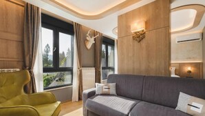 Una sala de estar moderna con un sofá gris, un sillón amarillo y un ventanal con cortinas.