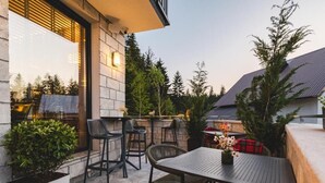 Un patio exterior con una mesa y sillas, una planta en maceta y vistas del entorno.