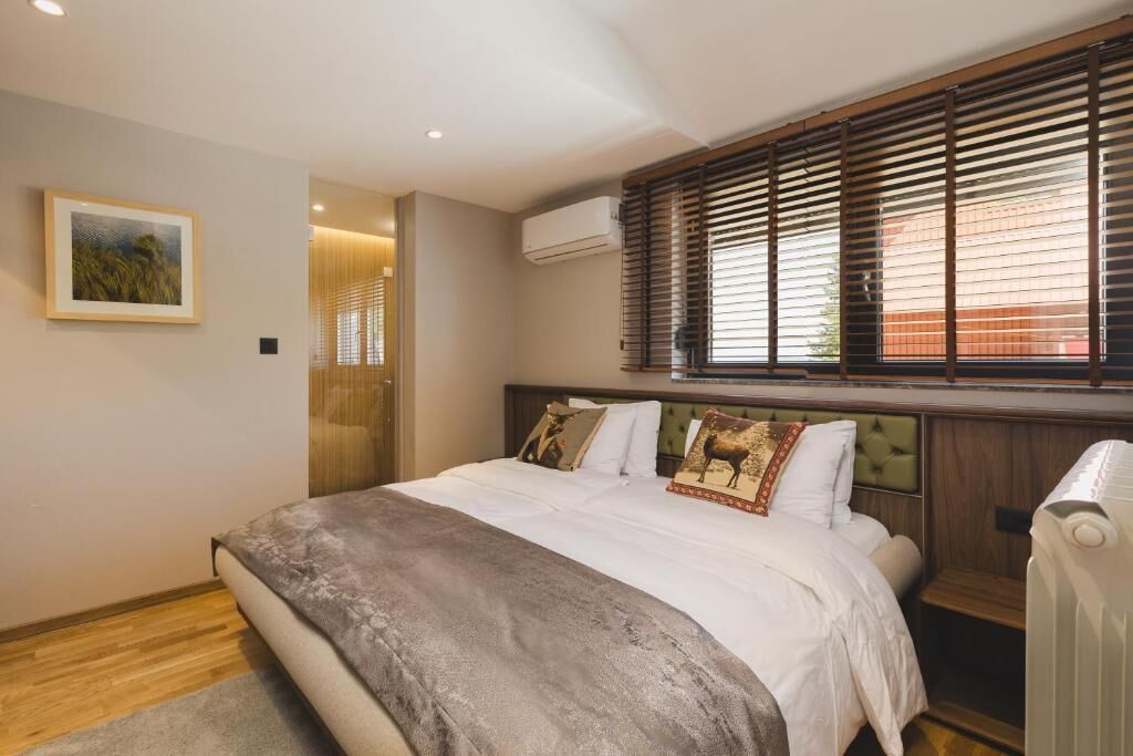 Ein Schlafzimmer mit Bett, einem Fenster mit Jalousien, einer Klimaanlage und einem gerahmten Bild an der Wand.
