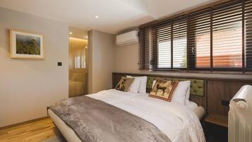 Ein Schlafzimmer mit Bett, einem Fenster mit Jalousien, einer Klimaanlage und einem gerahmten Bild an der Wand.