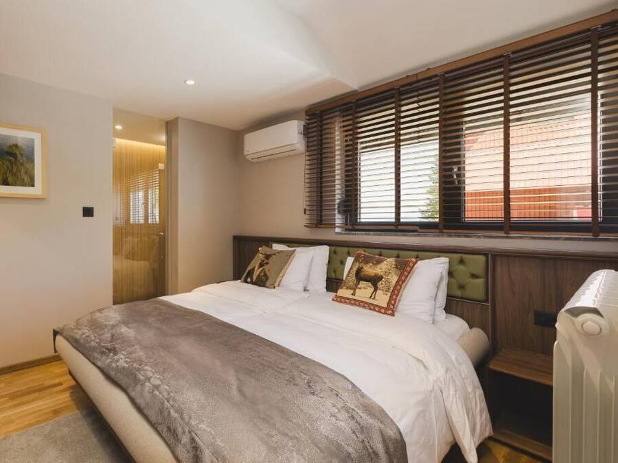 Ein Schlafzimmer mit Bett, einem Fenster mit Jalousien, einer Klimaanlage und einem gerahmten Bild an der Wand.