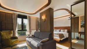 Una habitación de hotel moderna con sofá, cama, vistas al exterior y un espejo grande.