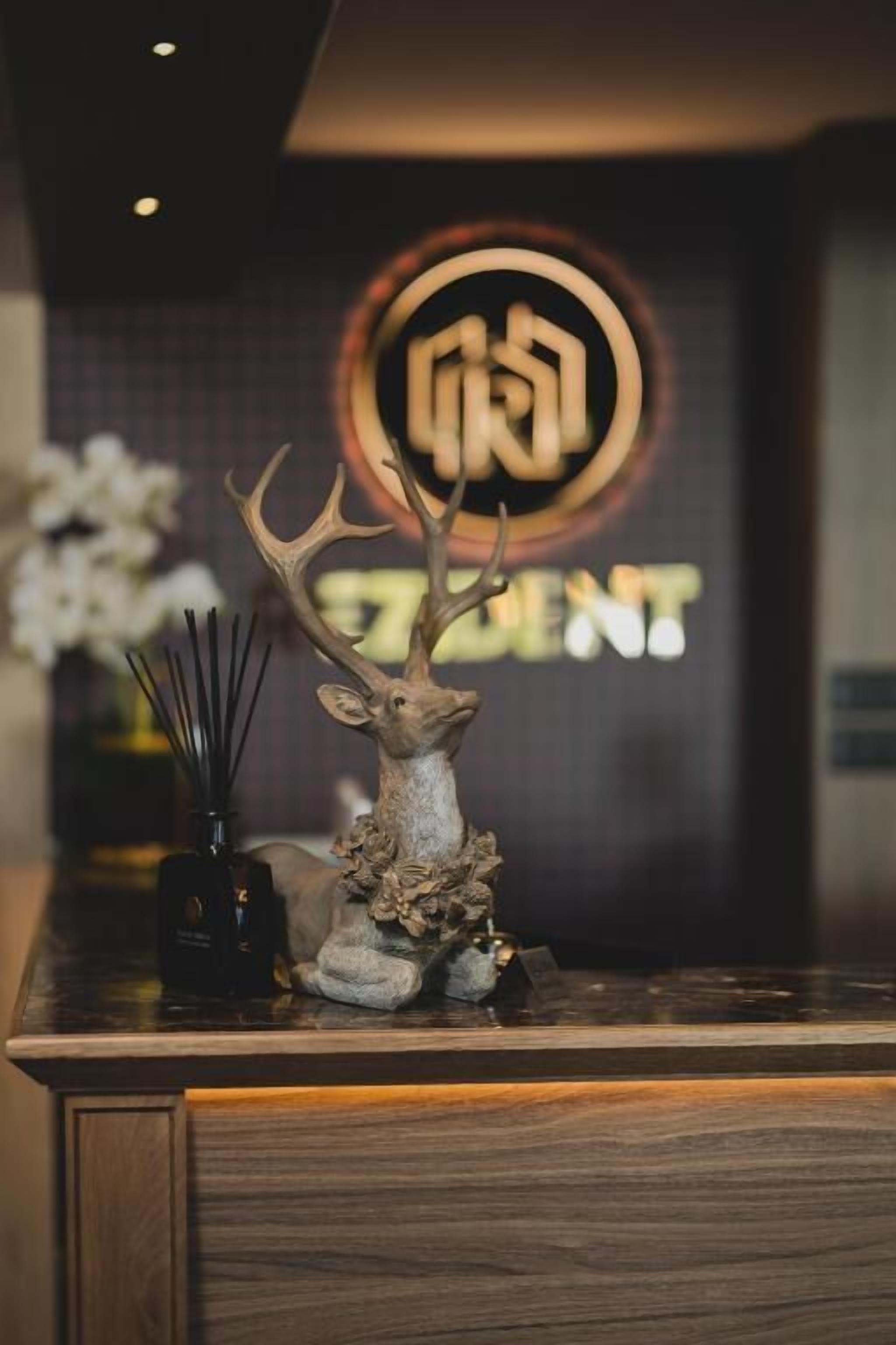 A reception desk with a deer head sculpture, a vase with flowers, and a sign with Chinese characters.