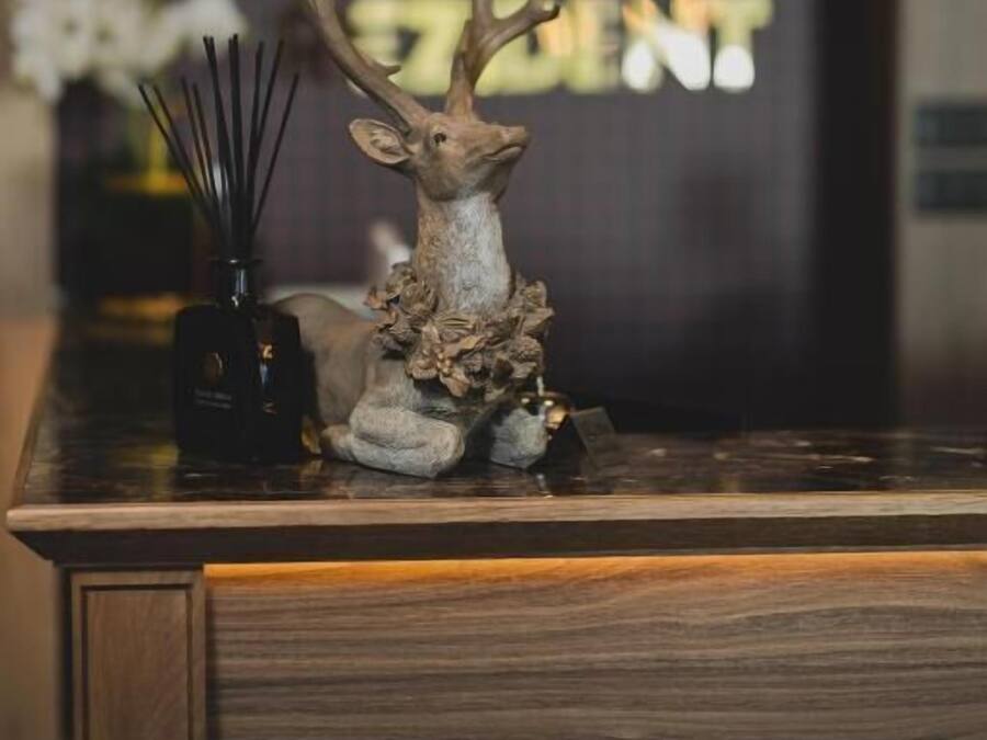 A reception desk with a deer head sculpture, a vase with flowers, and a sign with Chinese characters.