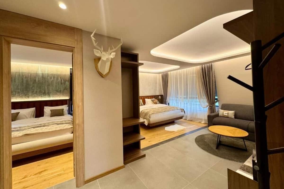 A modern hotel room with a bed, a sofa, a coffee table, and a staircase leading to another room.
