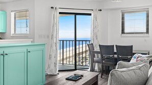 Ein Zimmer mit Balkon, einem Esstisch und einer Couch.