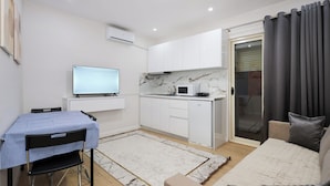 Un espacio habitable compacto con kitchenette, comedor y sofá.