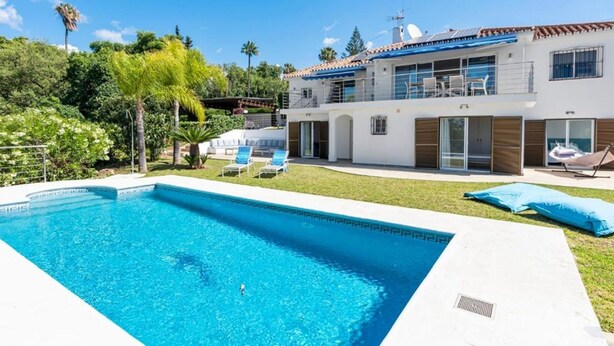 Et moderne hus med to etager, swimmingpool, overdækket terrasse og en velholdt have.