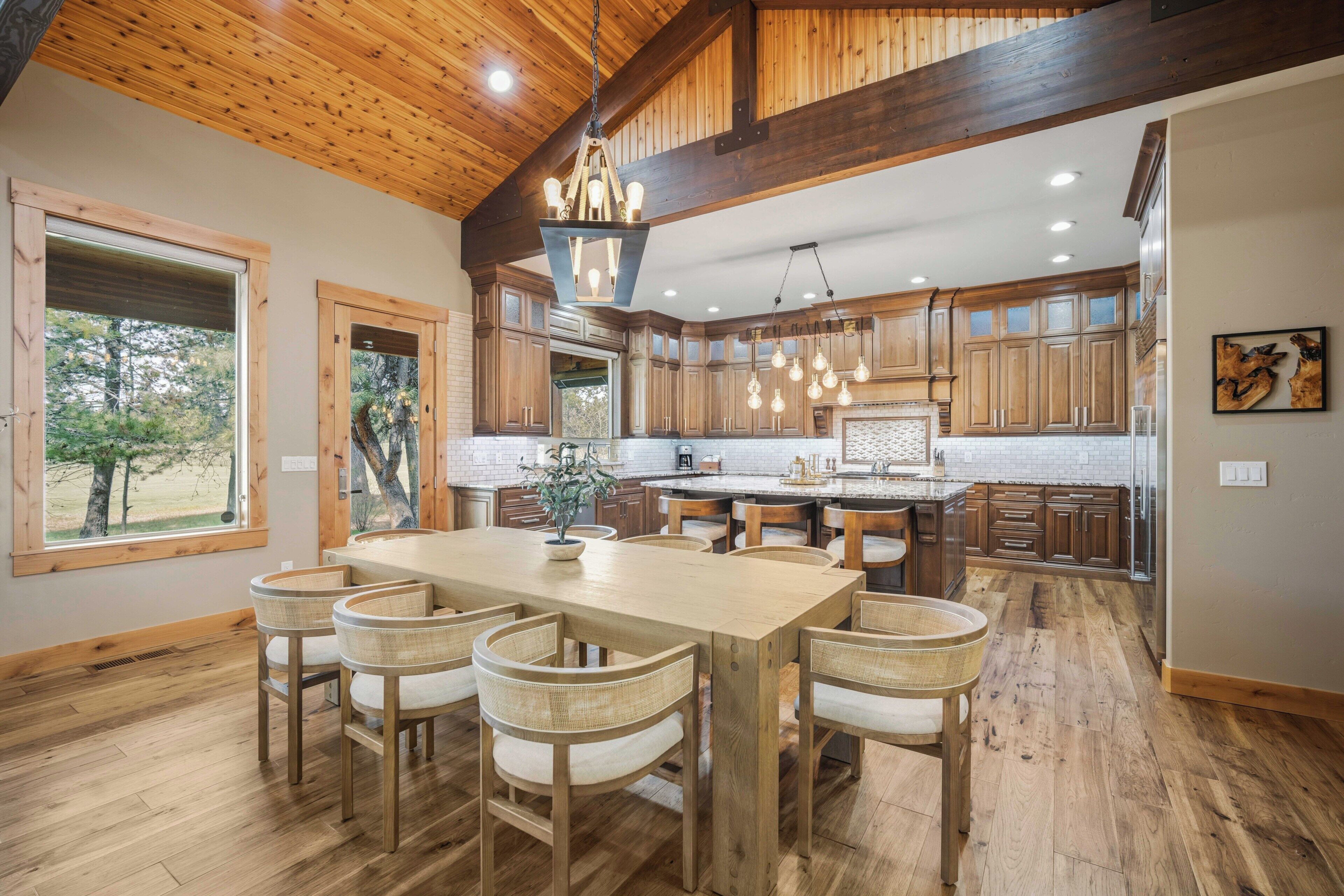 A spacious kitchen with wooden cabinets, a large island, and a dining area with chairs.