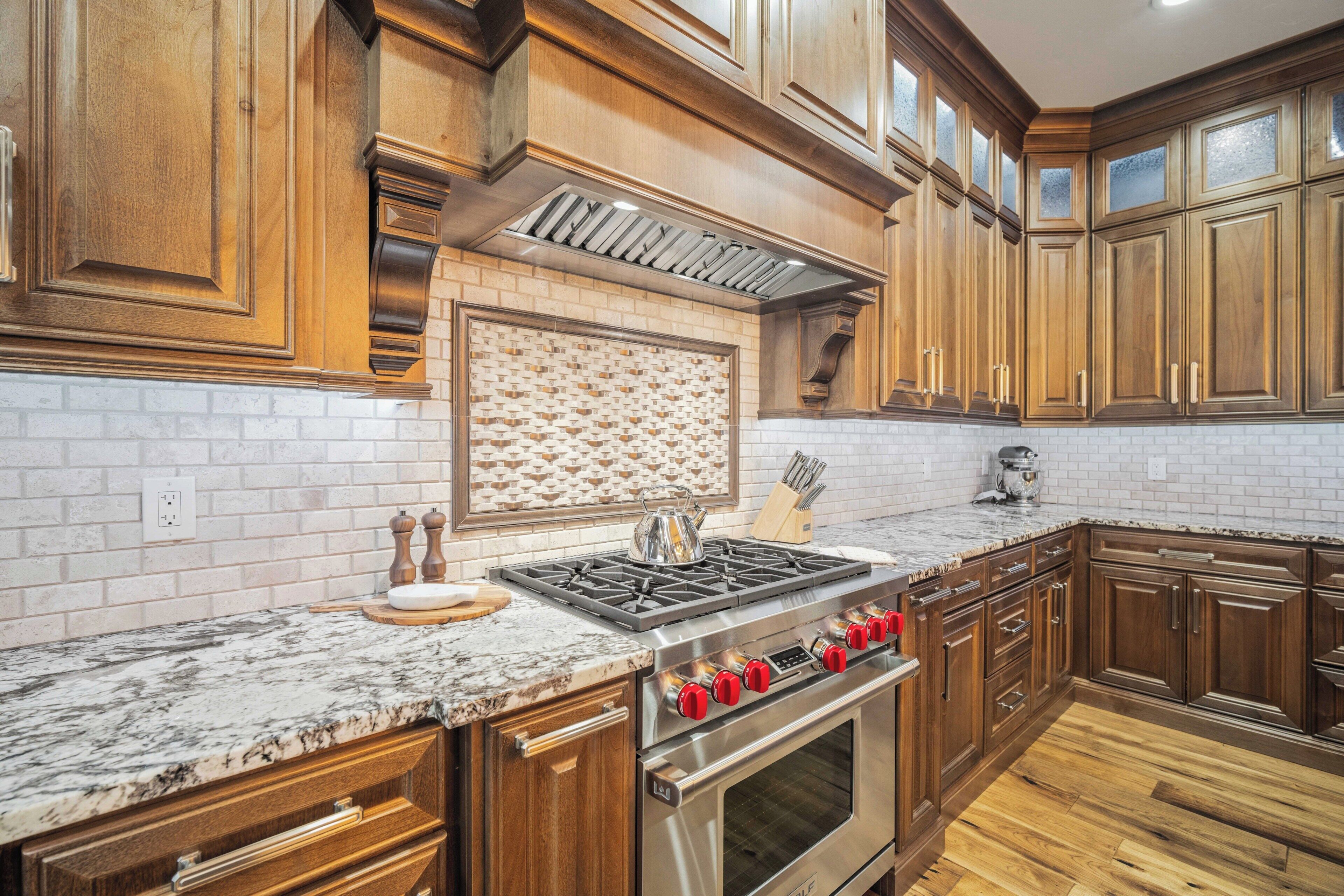Uma cozinha com armários de madeira, fogão de aço inoxidável e backsplash revestido de azulejos.