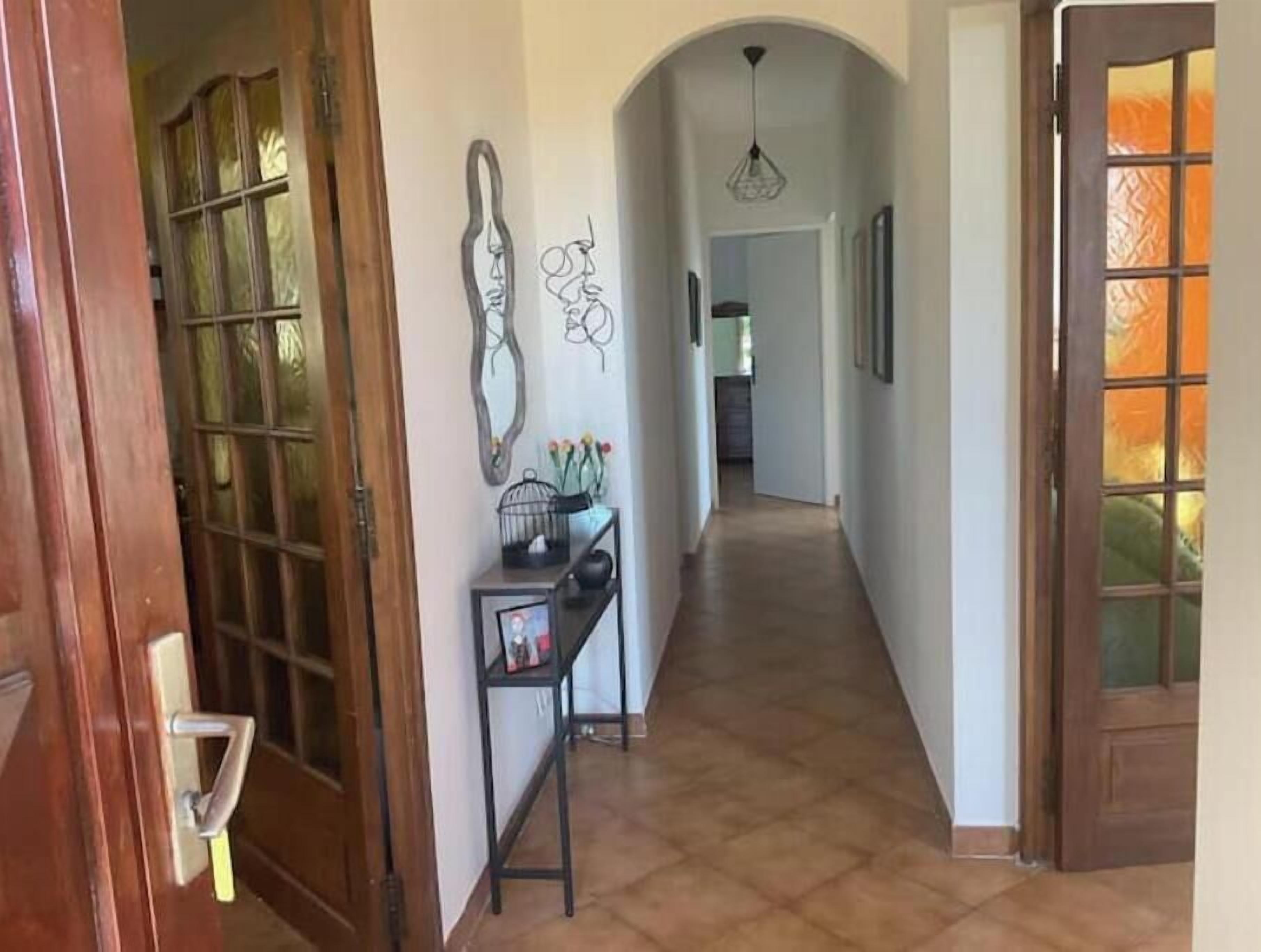 Un couloir avec une porte en bois, une console ornée d’objets décoratifs et un sol carrelé.