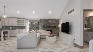 Uma sala de estar moderna com um sofá, uma televisão e uma lareira.