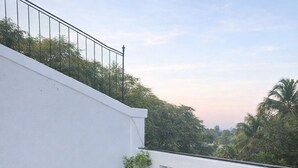 Un balcon agrémenté de meubles en osier et d’une plante en pot.