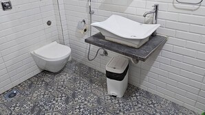 Une salle de bain avec des toilettes blanches, un lavabo et un miroir.