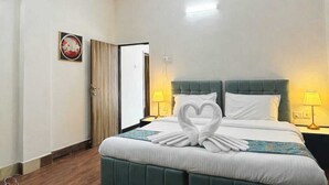 A hotel room with a bed, a ceiling fan, a nightstand with a lamp, and a door. - 3-bedroom villa in serene Mumbai perfect for relaxing getaways (Mumbai)