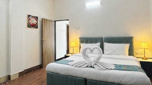 Une chambre d’hôtel avec un lit, un ventilateur de plafond, une table de chevet avec une lampe et une porte.