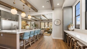Una cocina moderna con una isla central, taburetes de bar e iluminación colgante.