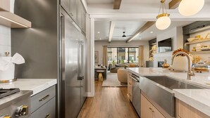 Una cocina moderna con electrodomésticos de acero inoxidable, una isla grande con un lavamanos y un comedor a la vista a través de un arco.