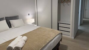 A modern hotel room with a large bed, a walk-in closet, and a bedside table with a lamp. - Penteada Golden Residence - Modern apartment near the center of Funchal (Funchal)