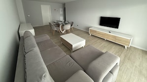 A modern living room with a sofa, a dining table, and a TV. - Penteada Golden Residence - Modern apartment near the center of Funchal (Funchal)