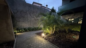 A paved pathway leading to a small garden area with a palm tree and other greenery. - Penteada Golden Residence - Modern apartment near the center of Funchal (Funchal)