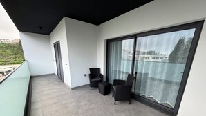 A balcony with grey tiled flooring, a black ceiling, and a large sliding glass door. - Penteada Golden Residence - Modern apartment near the center of Funchal (Funchal)