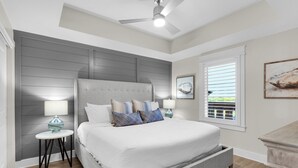 Un dormitorio con una cama grande, dos mesitas de noche, un ventilador de techo y una ventana con persianas.