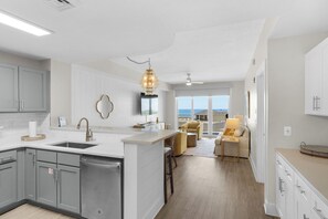 A modern kitchen with a central island, grey cabinets, and a view to the outside. - CALYPSO 3-711 Spectacular condo! Affordable rates! Inquire for details! (Panama City Beach)
