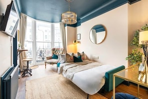 Une chambre à coucher avec un lit, une chaise, une table, un miroir et une fenêtre donnant sur un beau paysage.
