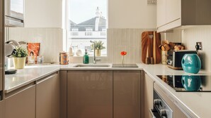 A modern kitchen with a window, a red rug, and various kitchen items. - Cosy Family Apartment 2 min from Hyde Park (London)