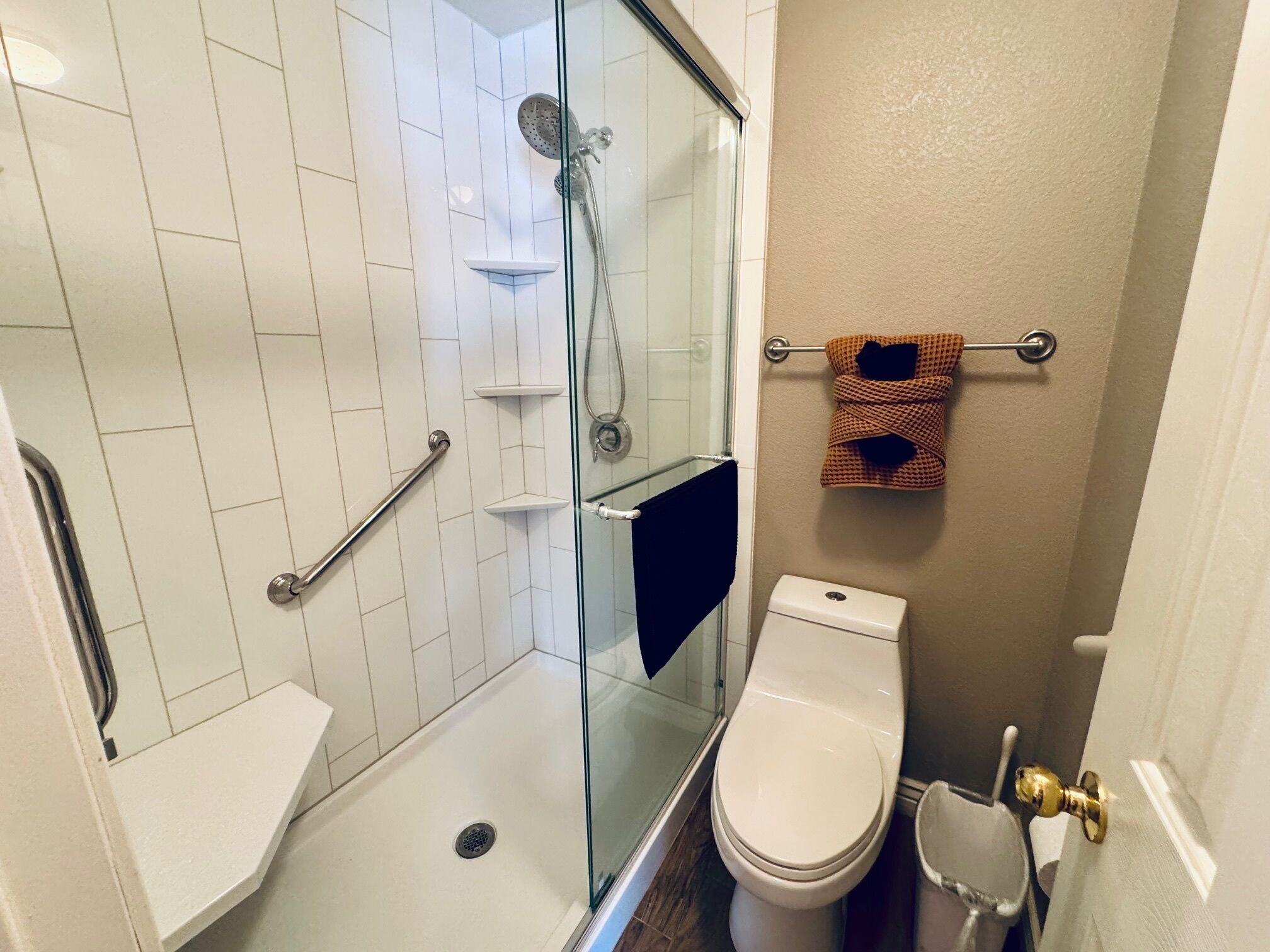 A bathroom with a glass-enclosed shower, a white toilet, and a towel rack with a patterned towel.