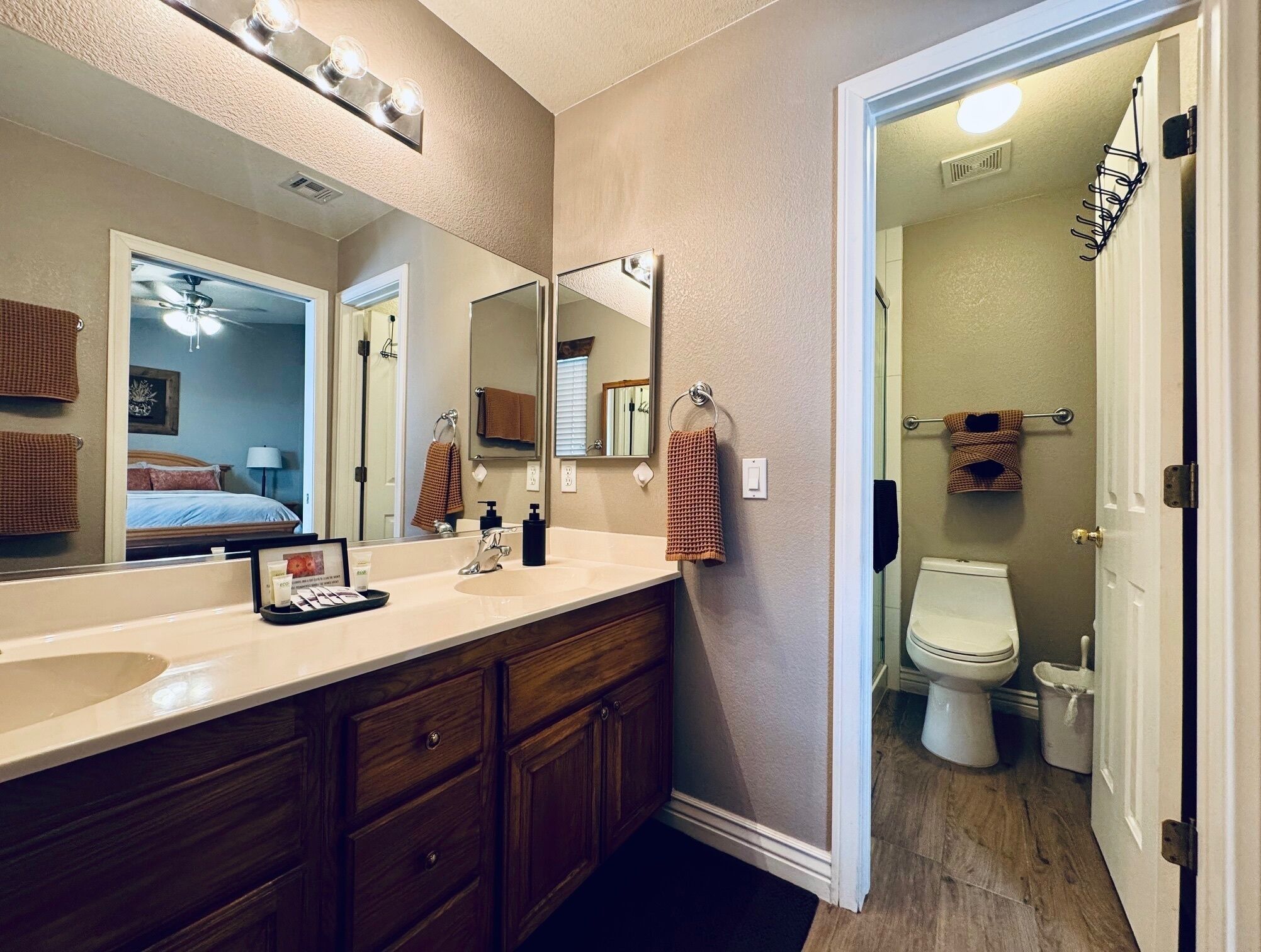 A bathroom with a large mirror, a sink, a toilet, and a shower area.