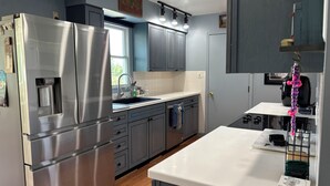 A modern kitchen with stainless steel appliances, grey cabinets, and a white countertop. - Private Sauna, Fireplace and Country Views (Mount Airy)