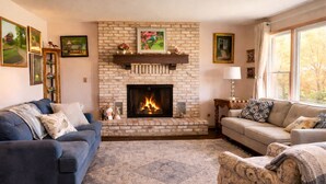 A living room with a fireplace, two sofas, a patterned rug, and framed artwork on the walls. - Private Sauna, Fireplace and Country Views (Mount Airy)