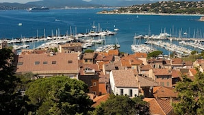 A coastal town with a marina filled with boats, terracotta-roofed buildings, and a clear view of the sea and distant hills. - Beautiful villa in the trees with air-con and pool (Les Arcs)