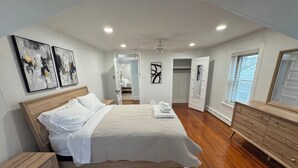 Un dormitorio con cama de madera, una mesita de noche, un aparador y un vestidor.