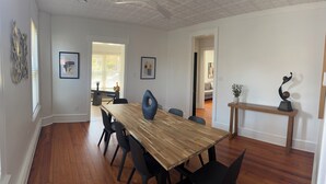 Un comedor con una mesa de madera, sillas negras y un ventilador de techo.
