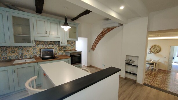 A modern kitchen with light blue cabinets, a central island, and a patterned backsplash.