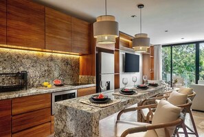 A modern kitchen with granite countertops, wooden cabinets, and pendant lighting. - Beautiful 2-bedroom apartment "Casa Lumina" in Narai Aldea Zama by HEUSHAVEN, Tulum. Features a private terrace, full kitchen, fast WiFi, rooftop pool, gym, and shared amenities. Prime location between downtown Tulum and the beach road. (Tulum)