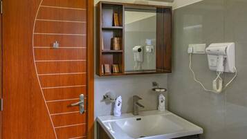 Un baño con puerta de madera, un lavamanos blanco, un espejo y un perchero para toallas.