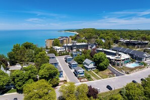A coastal residential area with a mix of modern and traditional architecture, a swimming pool, and a view of the sea.