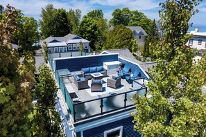 A rooftop deck with outdoor furniture, a pool, and a view of surrounding houses.