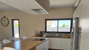 Una cocina moderna con una isla central, armarios blancos, un refrigerador de acero inoxidable y un ventanal con vistas.