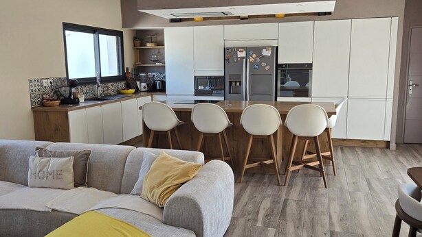 Una cocina moderna con armarios blancos, horno empotrado y refrigerador.