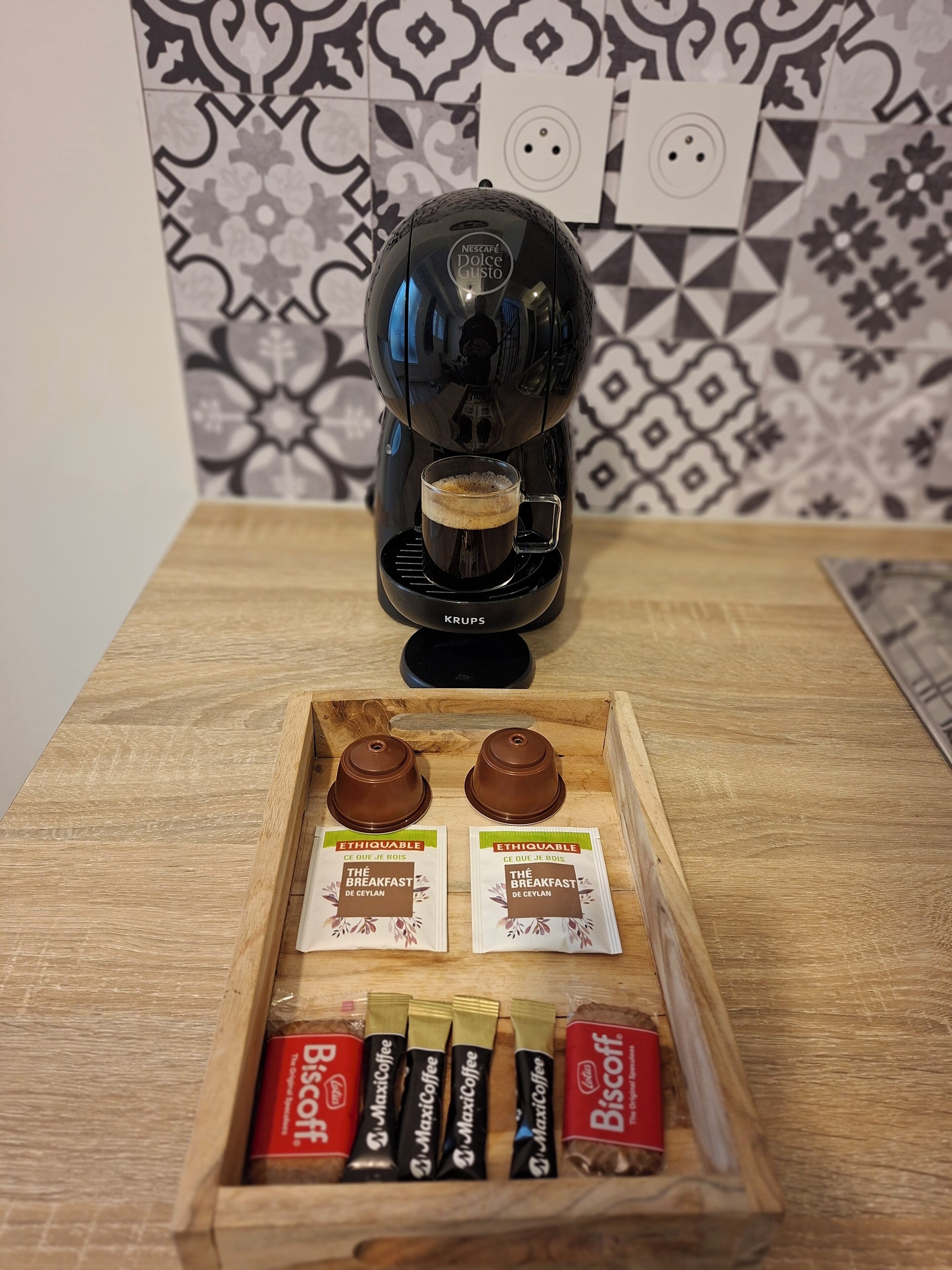 Een koffiezetapparaat op een houten tafel, met een dienblad koffiecups ervoor.